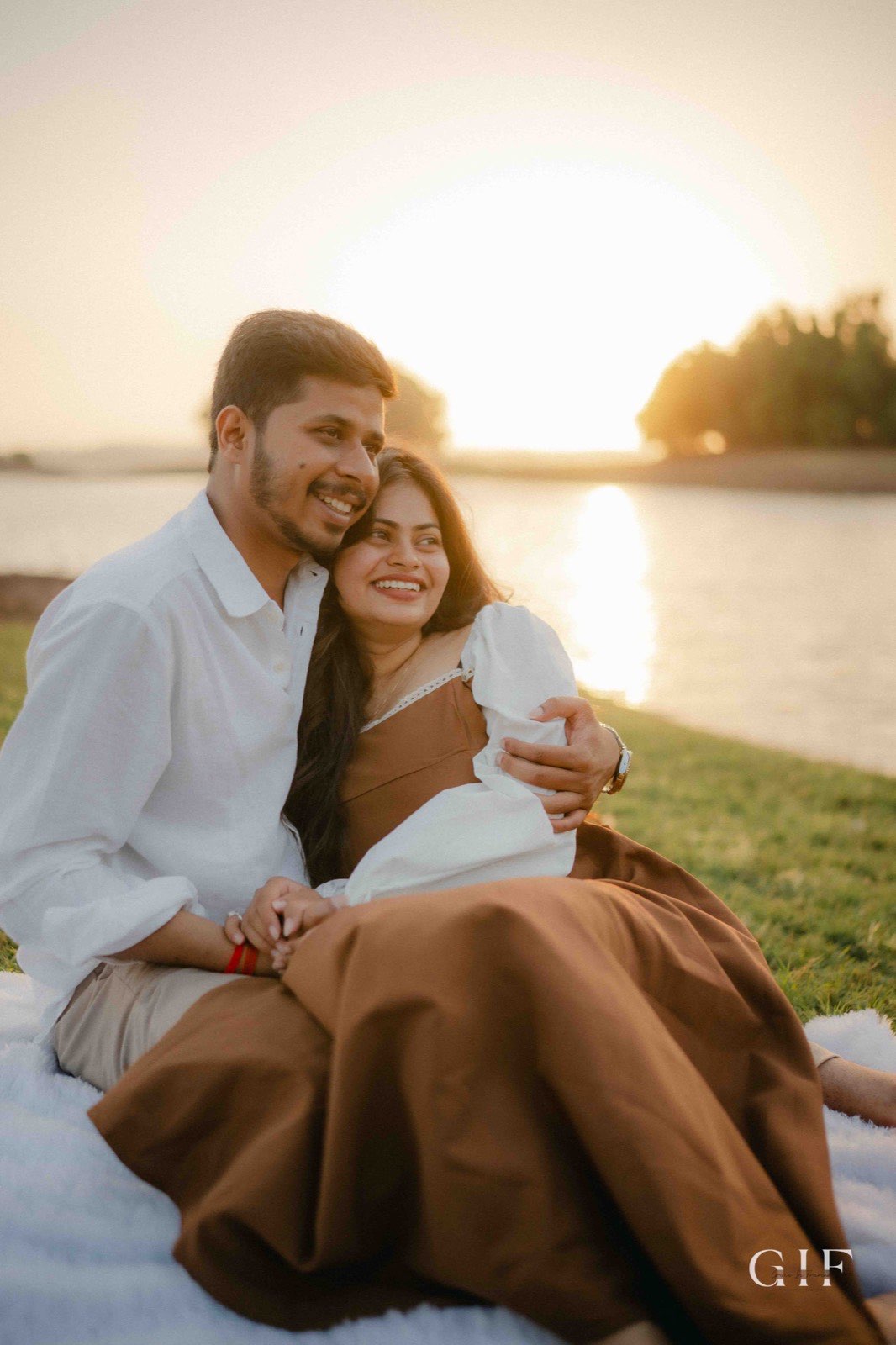 Niranjan and Pranali laughing beside a lake at sunset